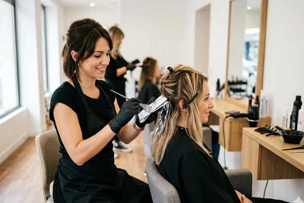 Coiffeuse réalisant une coloration dans un salon de coiffure en Moselle